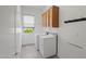 Bright laundry room with overhead cabinets, a hanging rack and a tile floor at 13134 W Los Bancos Ct, Sun City West, AZ 85375