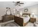 This primary bedroom features an ornate, wooden sleigh bed with tile floors and a ceiling fan at 15797 W Cinnabar Dr, Surprise, AZ 85374