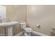 Powder room with a pedestal sink, round mirror, and modern toilet at 15812 W Lisbon Ln, Surprise, AZ 85379
