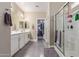 Bathroom featuring double sinks, a shower with glass doors, and a walk-in closet at 15812 W Lisbon Ln, Surprise, AZ 85379