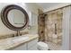 Updated bathroom featuring a granite countertop, decorative framed mirror, and tiled walk-in shower with pebble flooring at 16235 W Cottonwood St, Surprise, AZ 85374