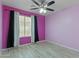 Bedroom with striking pink walls, tile floors, a ceiling fan, and a window with blinds and black curtains at 16235 W Cottonwood St, Surprise, AZ 85374