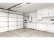 A clean garage with a roll-up door, white cabinets, and ample workspace at 16235 W Cottonwood St, Surprise, AZ 85374