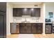 Modern kitchen features stainless steel appliances, including a dishwasher and wine fridge, with dark cabinets and granite countertops at 1644 W Roma Ave, Phoenix, AZ 85015