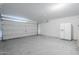Spacious garage with white walls, a roll-up door, and a white refrigerator at 17953 N Lettere Cir, Maricopa, AZ 85138
