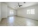 Bright living room with neutral tile flooring, ceiling fan, and natural light from large windows at 17953 N Lettere Cir, Maricopa, AZ 85138