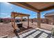 Landscaped backyard with pergola, a fire pit, seating, and a grill at 18586 N Lariat Rd, Maricopa, AZ 85138