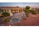 Backyard oasis featuring a covered patio, outdoor kitchen, flowing rock water feature, and desert landscaping at 22208 N San Ramon Dr, Sun City West, AZ 85375