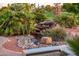 Backyard features a decorative rock waterfall and lush landscaping, perfect for outdoor enjoyment at 22208 N San Ramon Dr, Sun City West, AZ 85375
