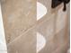 Close-up of neutral stone tiled shower with shelving in bathroom, neutral stone throughout at 22208 N San Ramon Dr, Sun City West, AZ 85375