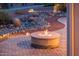 Inviting outdoor patio featuring a stone fire pit and desert landscaping at dusk at 22208 N San Ramon Dr, Sun City West, AZ 85375