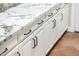 Close-up view of white cabinets, marble countertops, and black hardware at 22208 N San Ramon Dr, Sun City West, AZ 85375