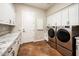 Laundry room with stainless steel washer and dryer, white cabinets, and marble countertop at 22208 N San Ramon Dr, Sun City West, AZ 85375