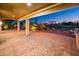 Covered patio with brick floors overlooking a water feature, green grass, palm trees and outdoor golf area at 22208 N San Ramon Dr, Sun City West, AZ 85375