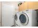 Functional laundry room with modern appliances, overhead cabinets, and an exterior door for convenience at 22232 N 48Th St, Phoenix, AZ 85054