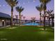 Stunning community pool surrounded by palm trees, lush green grass, string lights, and comfortable lounge areas at 2480 W Rowel Rd, Phoenix, AZ 85085