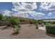 Landscaped backyard with gravel, mature trees, shrubs, and a pergola covered patio at 26017 W Maple Dr, Buckeye, AZ 85396