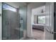 Modern bathroom with glass enclosed shower with bench and view into cozy bedroom at 26017 W Maple Dr, Buckeye, AZ 85396