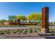 Welcoming entrance to Sun City Festival with desert landscaping, mature trees and unique steel monument features at 26017 W Maple Dr, Buckeye, AZ 85396