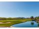Picturesque community golf course with a water feature, set against a mountain view under a clear, blue sky at 26017 W Maple Dr, Buckeye, AZ 85396