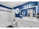White bathroom featuring tub with shower, stained glass window, and blue painted walls at 3209 E Fox St, Mesa, AZ 85213