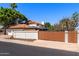Exterior home view with a tile roof, white walls, wood fence, and lush landscaping at 3209 E Fox St, Mesa, AZ 85213