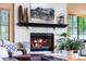 Close-up of a charming white brick fireplace with a dark mantle, decorative items, and cozy flames at 3209 E Fox St, Mesa, AZ 85213