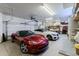 Well-lit garage featuring a red sports car, white car, utility sink, and plenty of storage space at 37809 N 9Th Pl, Phoenix, AZ 85086