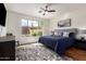 Bright bedroom featuring a large window, a queen bed with stylish pillows, and wood-look flooring at 41202 N Rolling Green Way, Anthem, AZ 85086