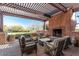 Relax on this covered patio with a stone fireplace and views of the manicured backyard and desert landscape at 41202 N Rolling Green Way, Anthem, AZ 85086