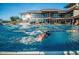 Bright open clubhouse with a beautiful outdoor pool and person swimming laps on a clear day at 41202 N Rolling Green Way, Anthem, AZ 85086