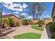 Landscaped backyard with brick pathway, artificial grass, desert landscaping, and a relaxing hot tub area at 45028 W Cypress Ln, Maricopa, AZ 85139