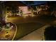 Night view of a paved driveway with manicured landscaping and landscape lighting at 45028 W Cypress Ln, Maricopa, AZ 85139