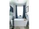 Clean bathroom featuring a sleek white bathtub with black fixtures and a window with patterned blue curtains at 4817 N 35Th St, Phoenix, AZ 85018
