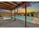 Covered outdoor patio with wood beams overlooks pool and backyard at sunset at 5126 W Las Palmaritas Dr, Glendale, AZ 85302