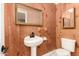 Small bathroom featuring a pedestal sink, decorative mirrors, and wood-paneled walls at 632 N 95Th St, Mesa, AZ 85207