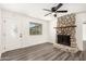 Bright living room with stone fireplace, gray wood floors, ceiling fan, and front door at 632 N 95Th St, Mesa, AZ 85207