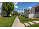 Sidewalk view of complex with mature trees and grassy areas on sunny day at 7350 N Via Paseo Del Sur -- # O202, Scottsdale, AZ 85258