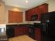 A kitchen featuring sleek black appliances, granite countertops, and rich cherry wood cabinetry at 7521 S 31St Pl, Phoenix, AZ 85042