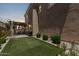Serene backyard featuring an artificial grass area, covered patio, and meticulously maintained landscaping at 9733 E Axle Ave, Mesa, AZ 85212