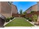 Neat backyard showcasing an artificial lawn, trimmed shrubbery, and a secure fenced perimeter at 9733 E Axle Ave, Mesa, AZ 85212