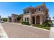 Two-story home features a tile roof, arched entryway, manicured landscaping, and beautiful stone accents at 9733 E Axle Ave, Mesa, AZ 85212
