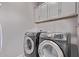 Well-equipped laundry room with high-efficiency washer and dryer and ample overhead cabinet storage at 9733 E Axle Ave, Mesa, AZ 85212