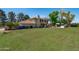 Large backyard featuring manicured lawn, the home's exterior, a covered patio, and mature trees at 10532 W Catalina Dr, Avondale, AZ 85392