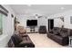 Well-lit living room featuring a ceiling fan, TV, fireplace, tile flooring, and comfortable leather seating at 10532 W Catalina Dr, Avondale, AZ 85392