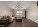 Spacious living room featuring dark hardwood flooring, a white sofa with orange pillows, and a modern ceiling fan at 11025 N 45Th Ln, Glendale, AZ 85304
