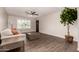 Bright and airy living room with dark hardwood flooring, a white sofa with orange pillows, and a modern ceiling fan at 11025 N 45Th Ln, Glendale, AZ 85304