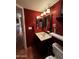 Bathroom featuring a vanity with a cream-colored sink, decorative mirror, and red painted walls at 12123 W Bell Rd # 337, Surprise, AZ 85378