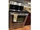 A Maytag stainless steel oven with a black stovetop and dark wood cabinets with a colorful towel at 12123 W Bell Rd # 337, Surprise, AZ 85378