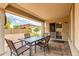 Covered patio with a table and chairs overlooking the brick paved backyard and sliding glass door at 14205 N 136Th Ln, Surprise, AZ 85379